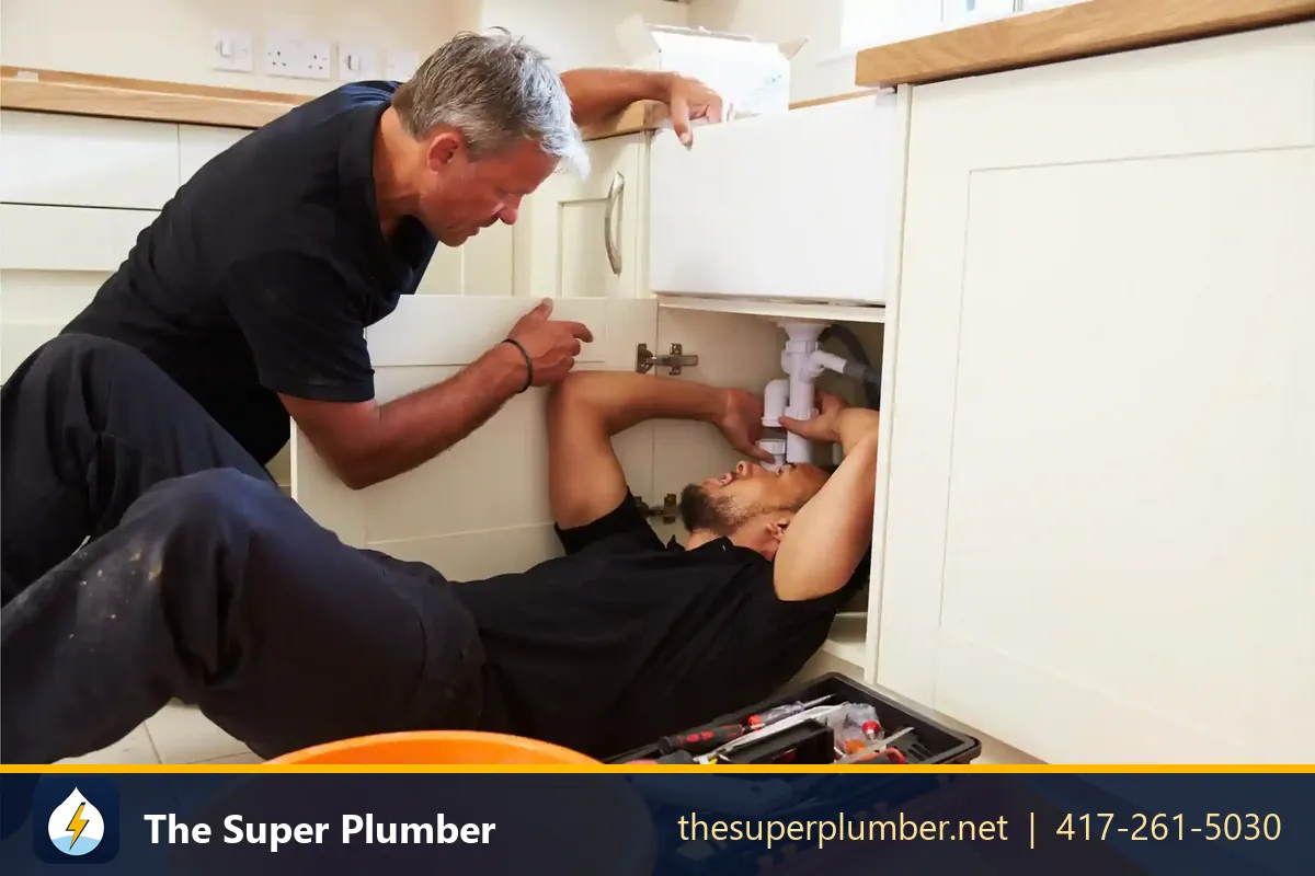 Two plumbers working under a kitchen sink - plumbing services