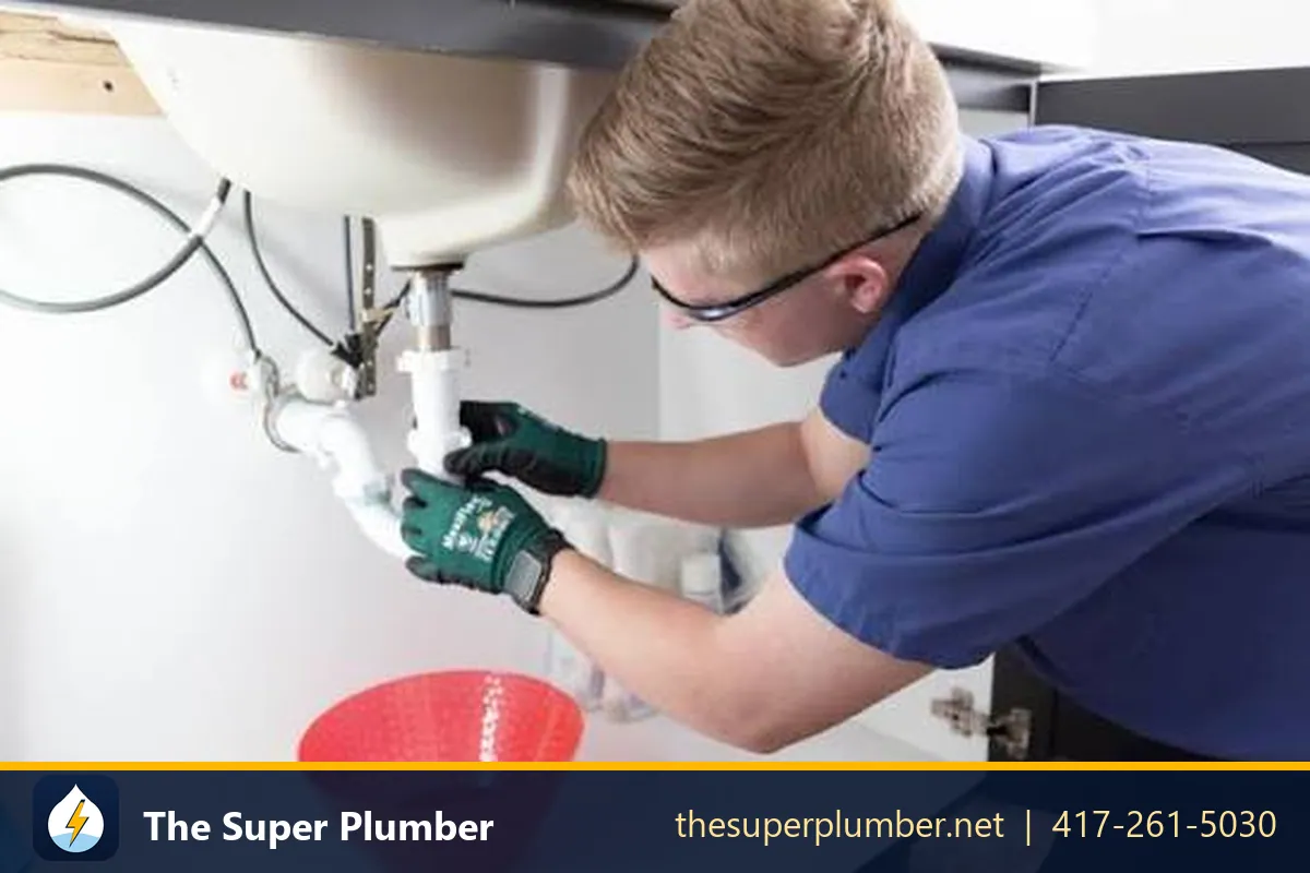 Plumber in gloves and safety glasses disconnecting a P-trap over a bowl - emergency plumber Scottsdale