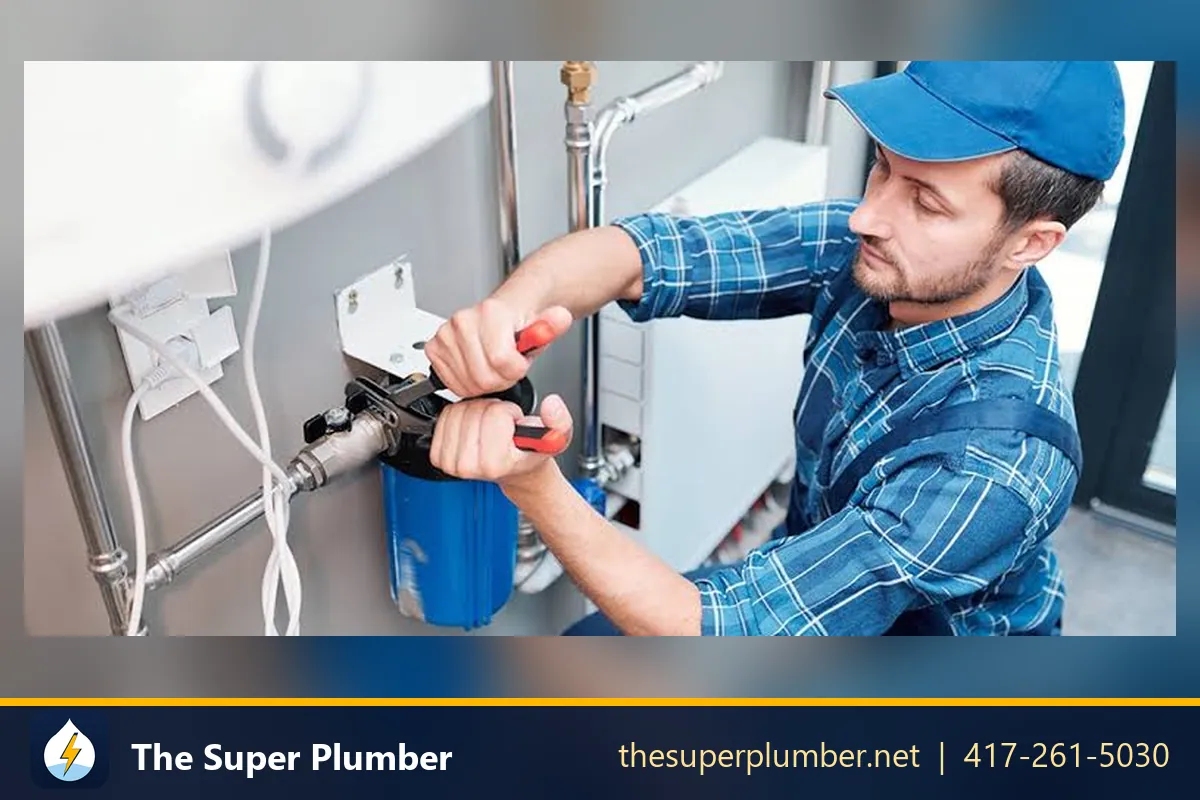 Plumber in a blue cap fitting a water filter housing with a wrench - Kennewick plumbing repair