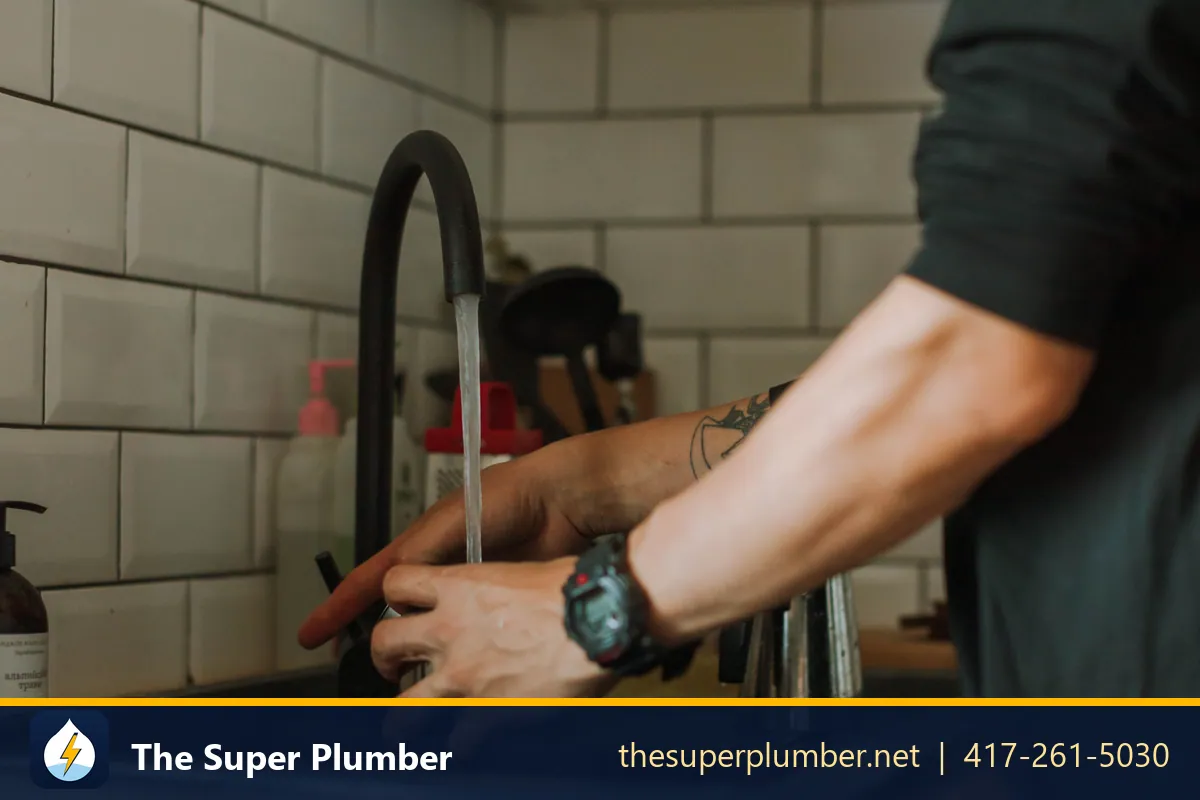 Hands adjusting a black gooseneck kitchen faucet - plumber in New York