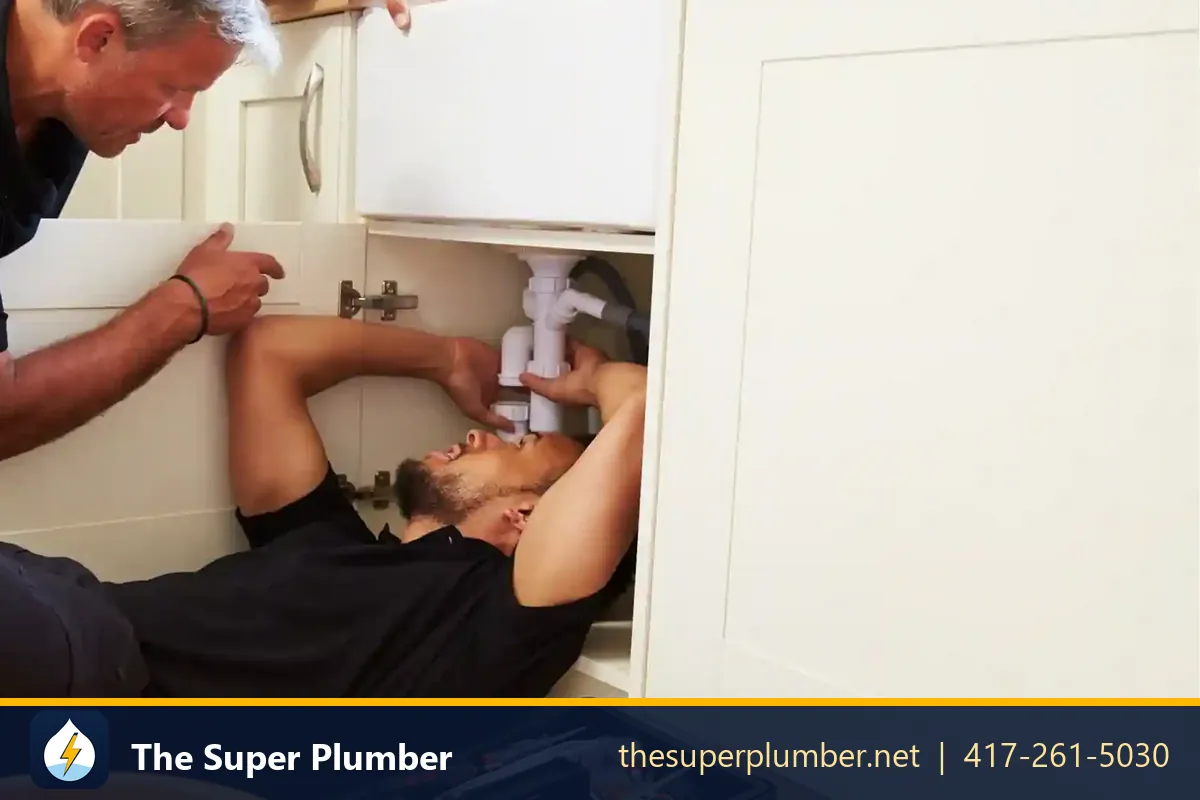 Two plumbers working under a kitchen sink - San Francisco plumbing repair