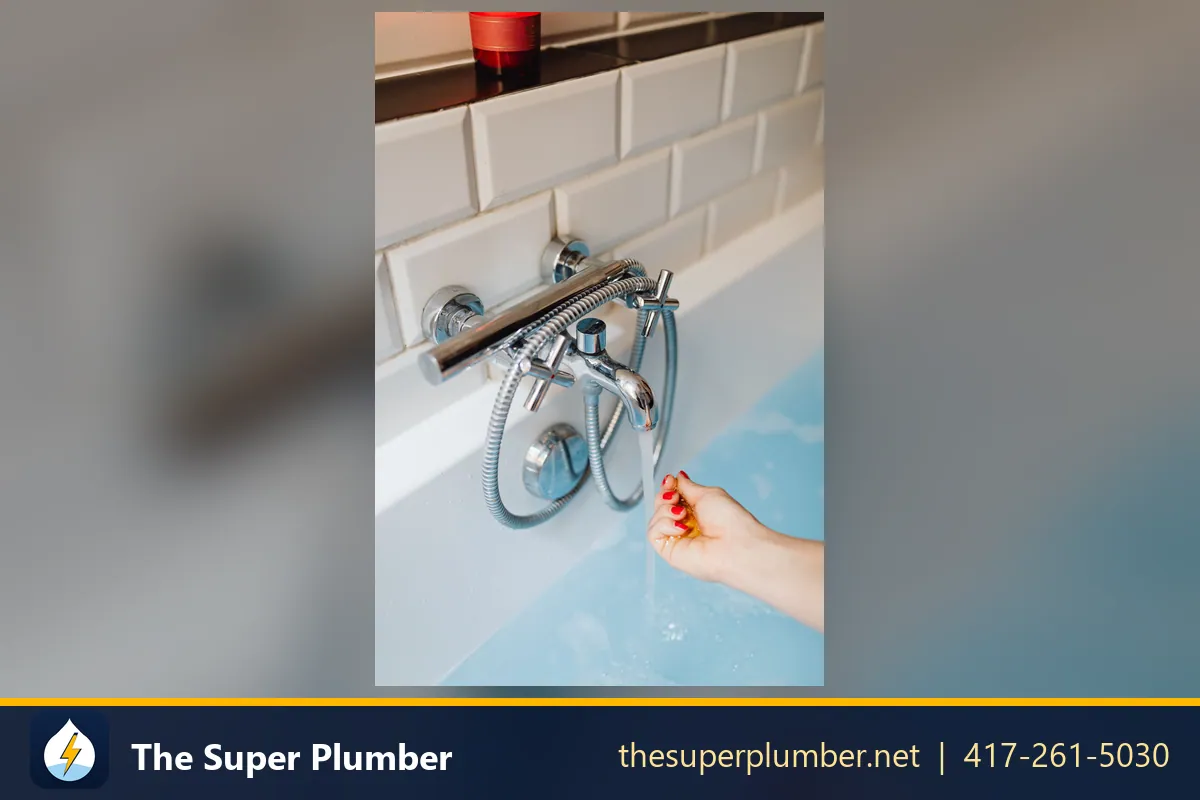 Bathtub faucet with a shower hose and a hand testing the water - Scottsdale plumbing repair