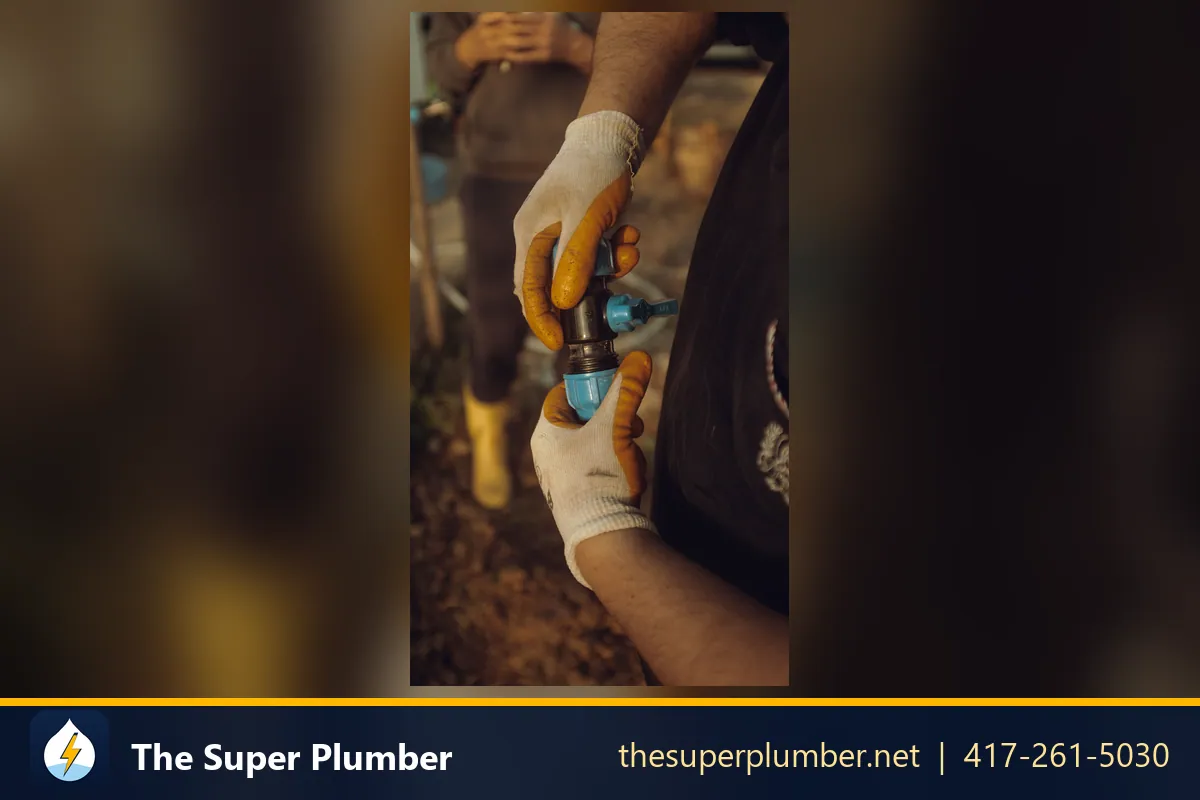 Gloved hands tightening a brass and blue plastic connector outdoors - backflow valve