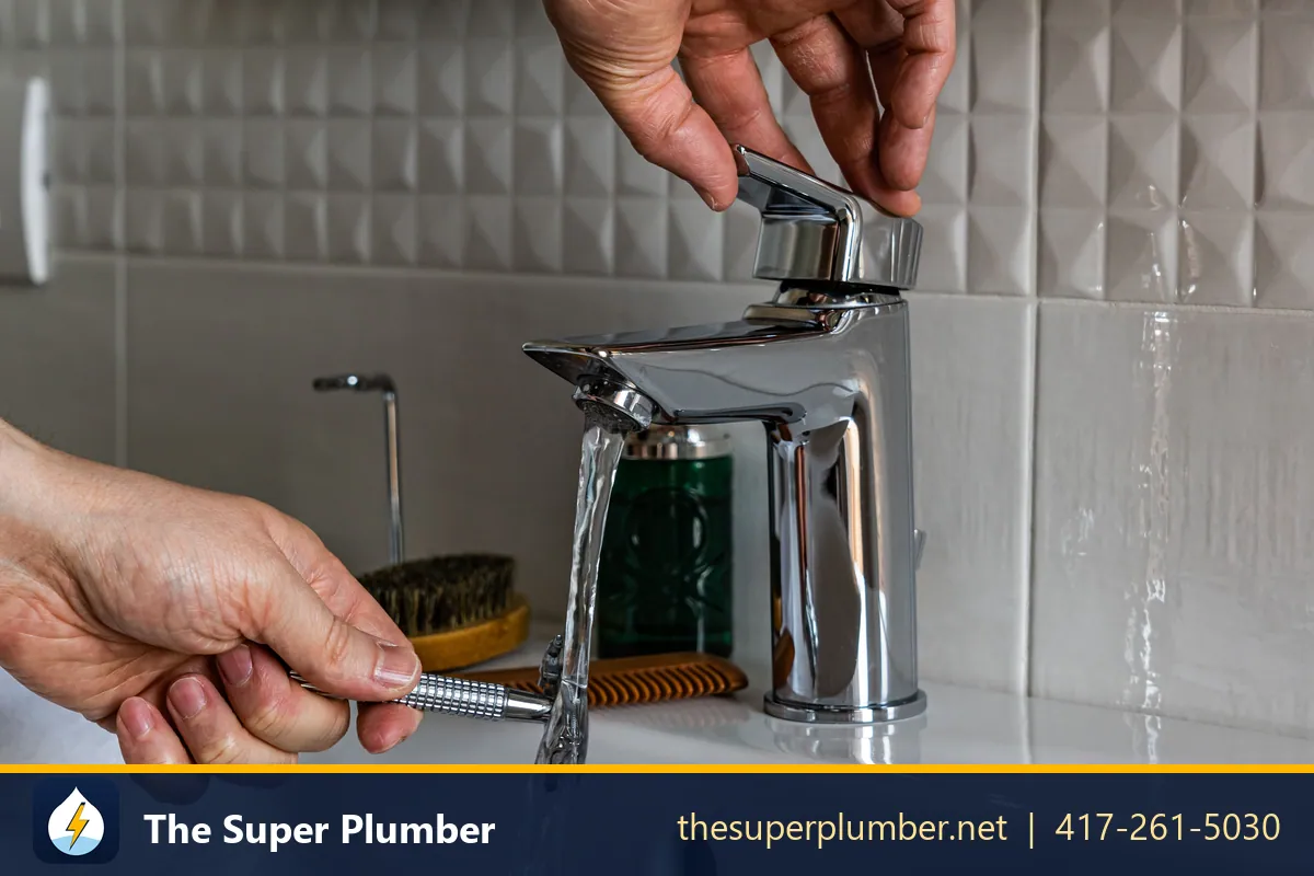 Hands tightening a chrome mixer tap with a small tool while water runs - how to change a kitchen faucet