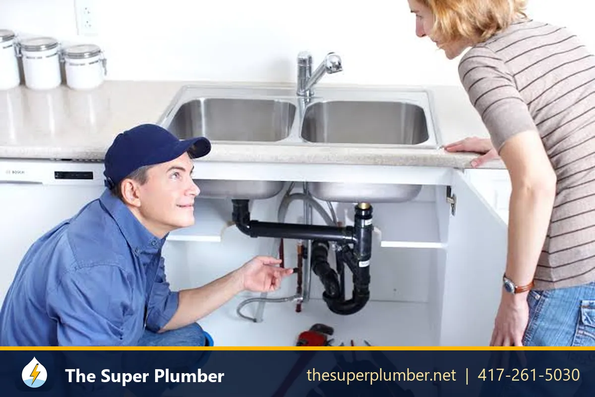 Plumber showing a homeowner the pipes under a kitchen sink - plumber for garbage disposal repair