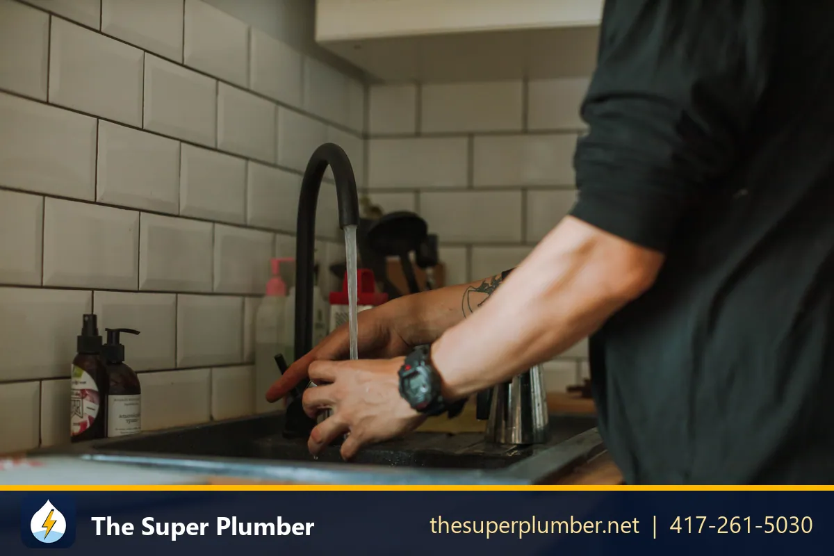 Hands adjusting a black gooseneck kitchen faucet - point of use water heater