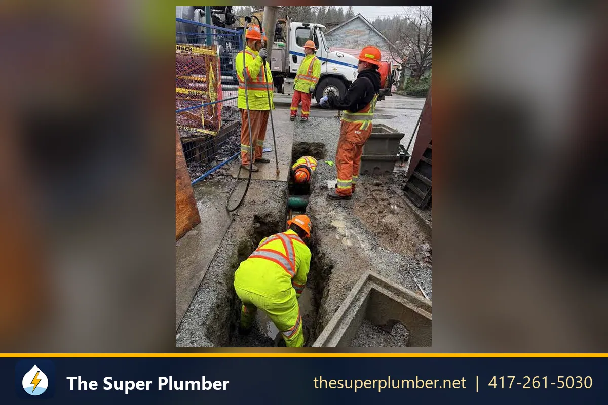 Utility crew in high-visibility gear around a street excavation over a buried pipe - sewer repair